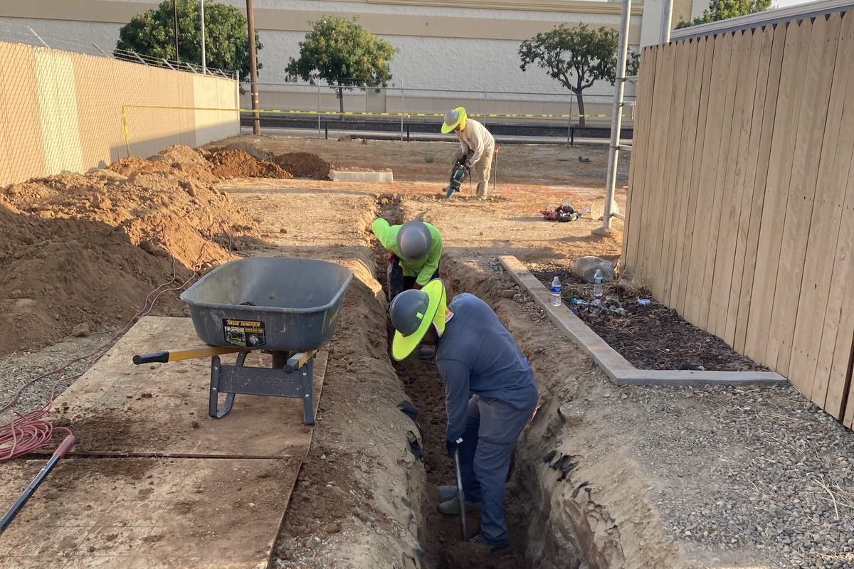 JMES crew hand-trenching for underground conduit installation