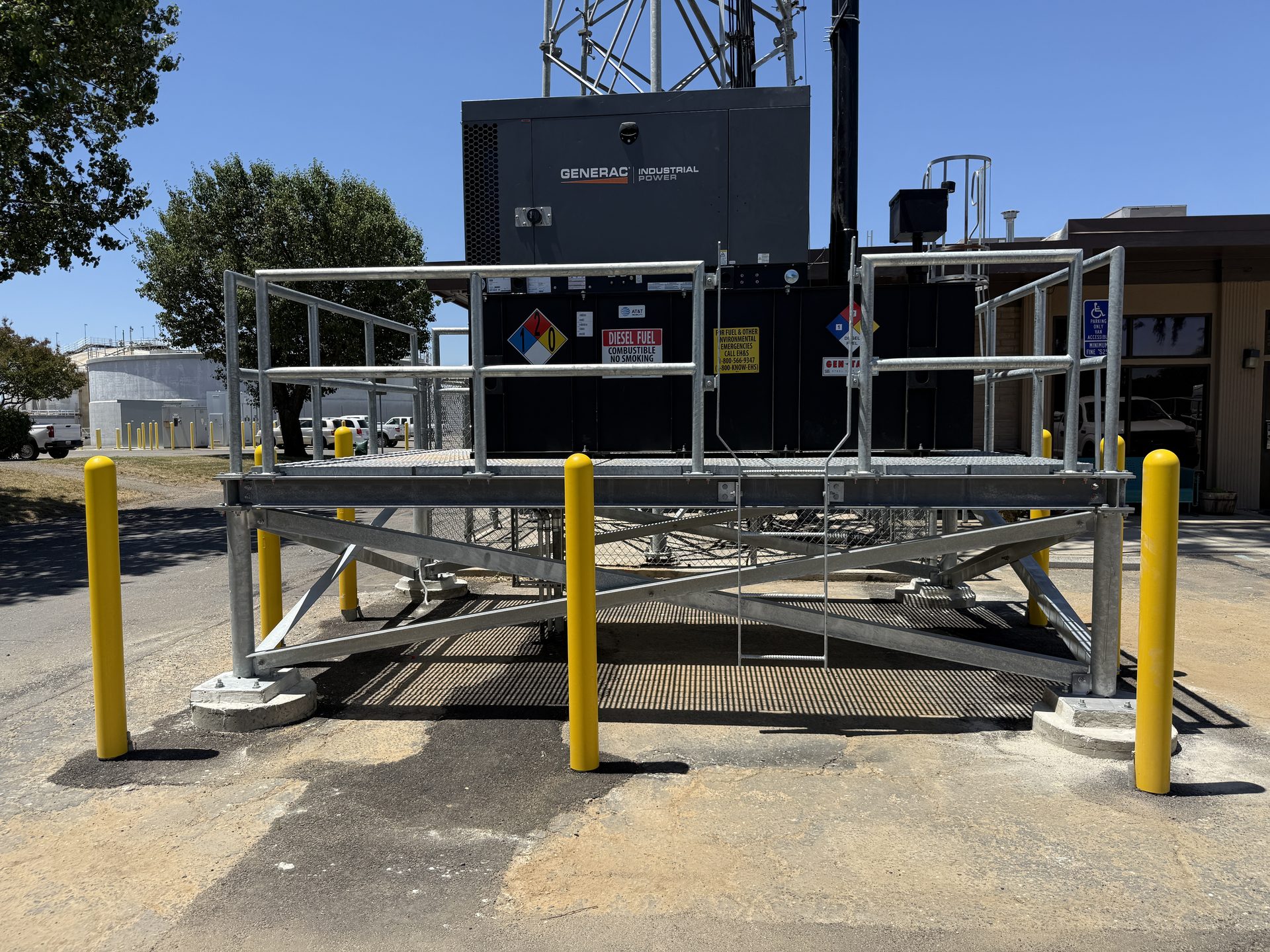Elevated generator platform with galvanized railings and safety bollards at a carrier site