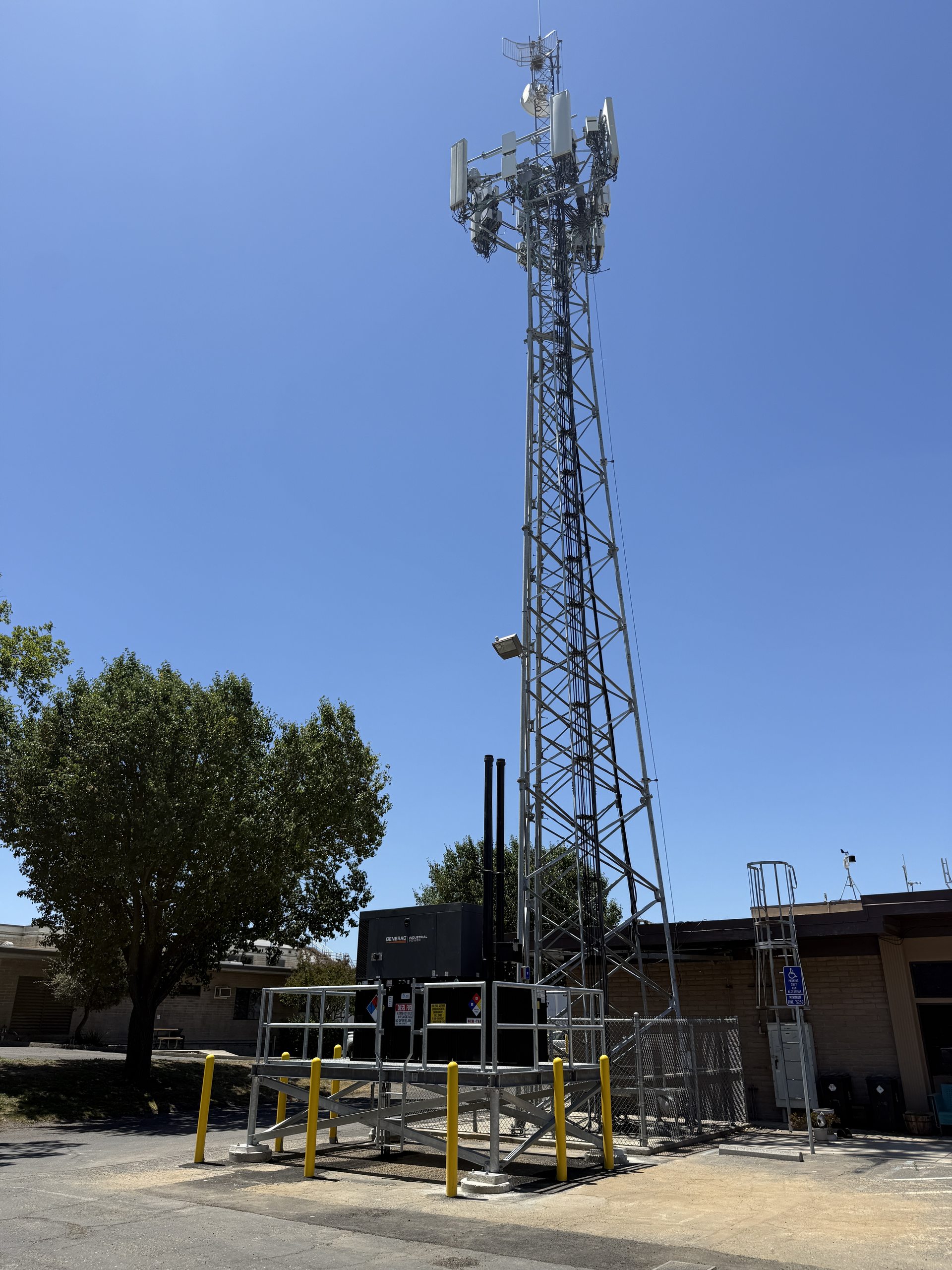 Full cell tower with antennas and elevated backup generator platform at its base