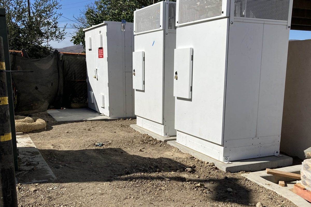 Power equipment cabinets set on concrete pads at an EV charging site